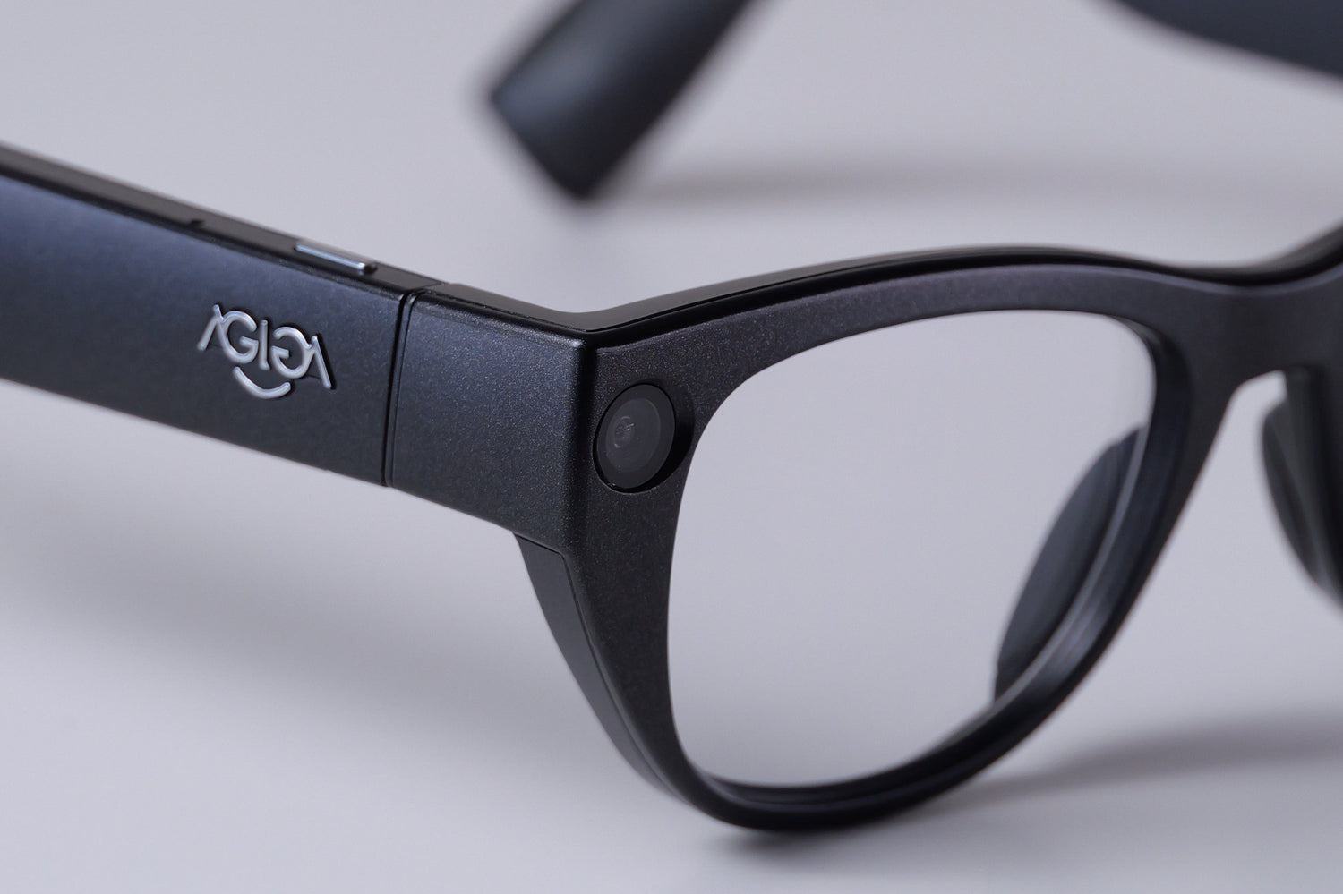 A close-up of the black EchoVision smart glasses on a white background. The image is centered on the discreet camera lens, which is integrated into the frame near the hinge of the right temple.